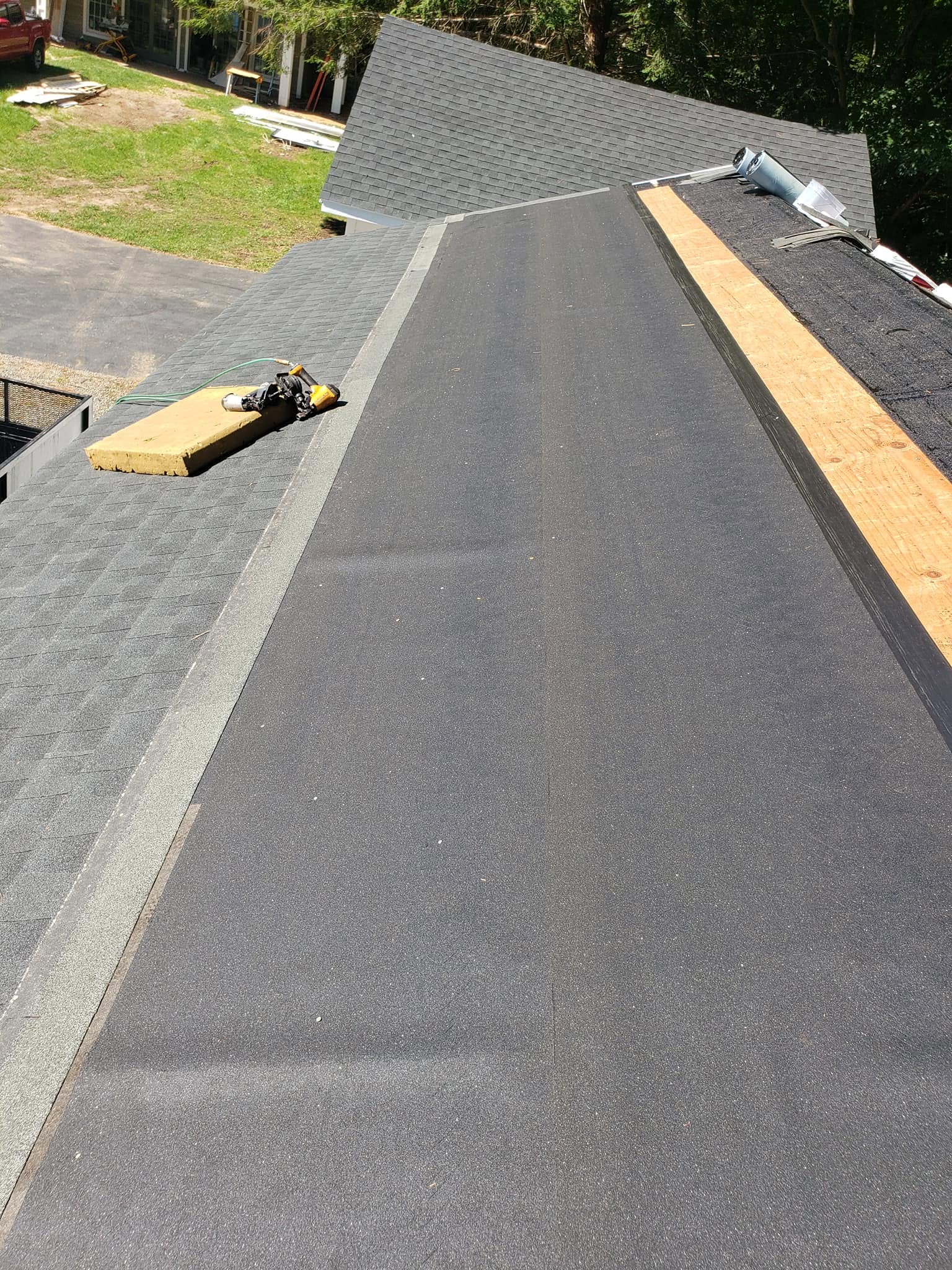 Roof replacement in progress showing new dark shingles and wooden boards on residential home