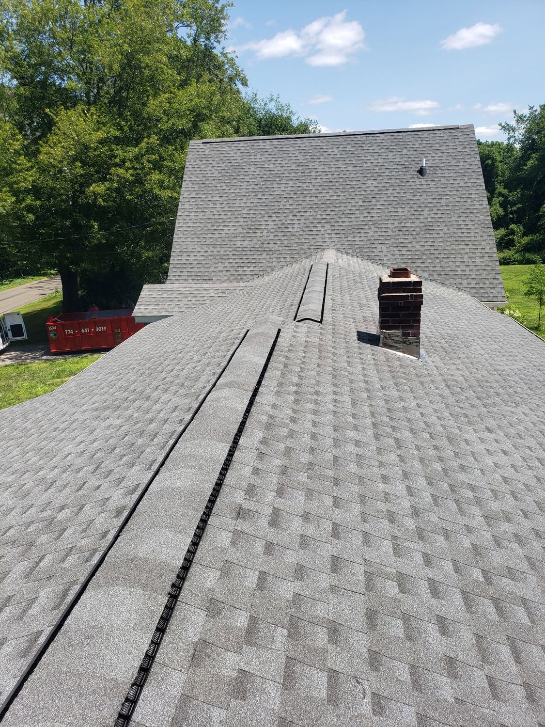 New asphalt shingle roof installation on residential home with brick chimney